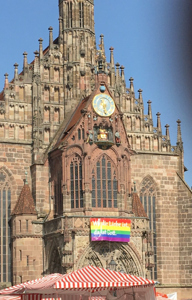 Regenbogenfahne an der Frauenkirche mit der Aufschrift: Wo die Liebe ist, da ist Gott.